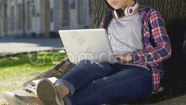 混合种族的学生坐在笔记本电脑露天做毕业设计